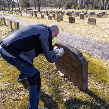 This image illustrates a professional inspection of a gravestone's condition. The process involves carefully checking the stability, alignment, and surface integrity to ensure the gravestone remains secure and well-maintained over time.