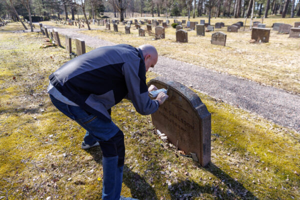 This image illustrates a professional inspection of a gravestone's condition. The process involves carefully checking the stability, alignment, and surface integrity to ensure the gravestone remains secure and well-maintained over time.